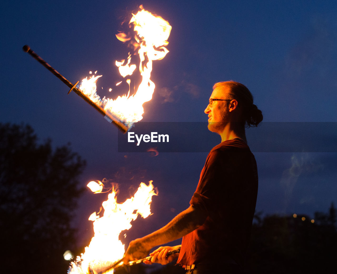 LOW ANGLE VIEW OF ILLUMINATED WOMAN STANDING AGAINST SKY AT NIGHT