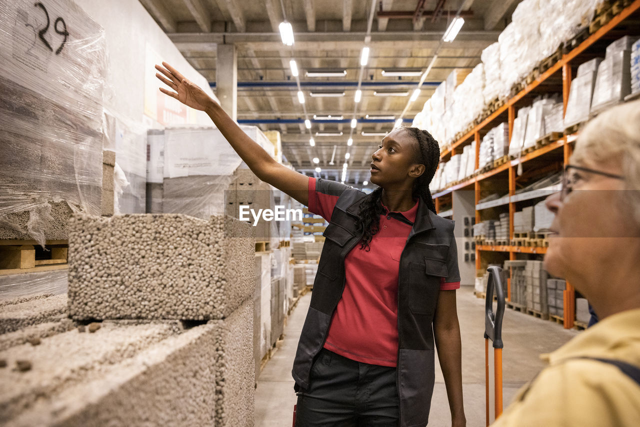 Saleswoman talking with female customer near concrete block at hardware store
