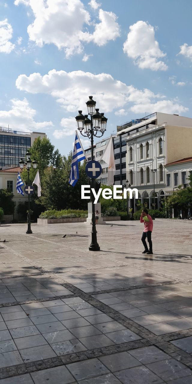 PEOPLE WALKING ON FOOTPATH BY BUILDINGS AGAINST SKY