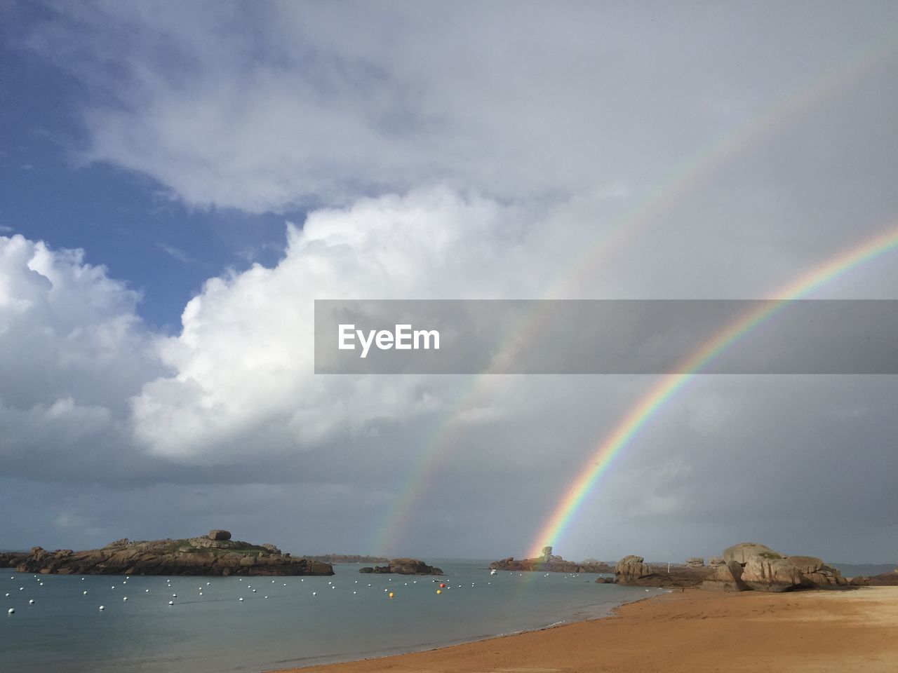 Scenic view of sea against cloudy sky with rainbow