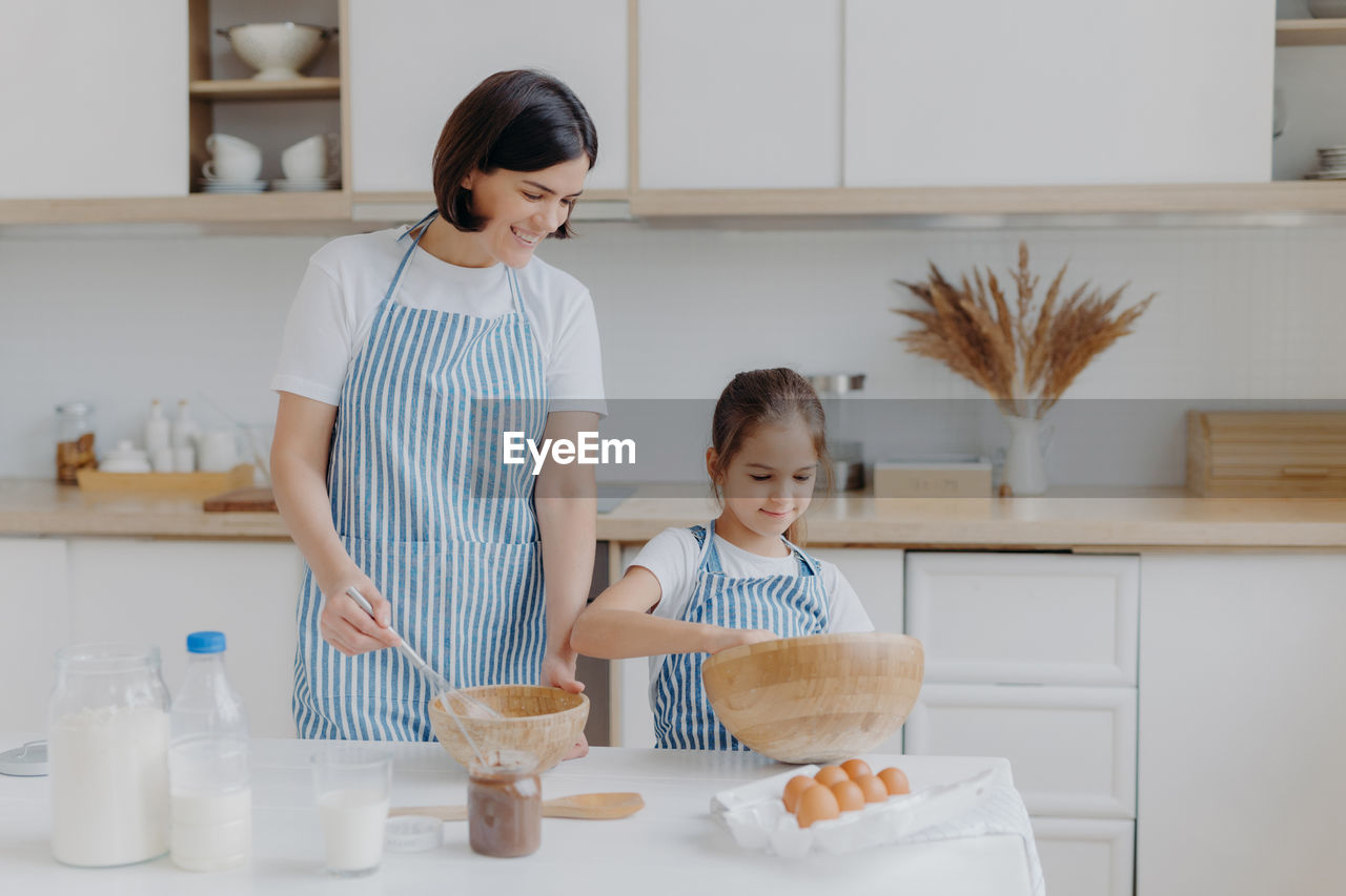 Mother with daughter preparing food in kitchen