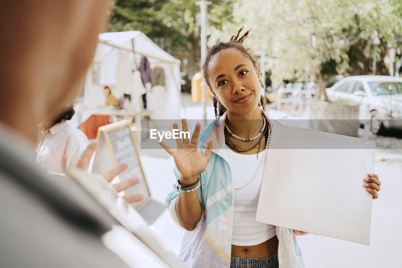 Female customer bargaining while holding record at flea market