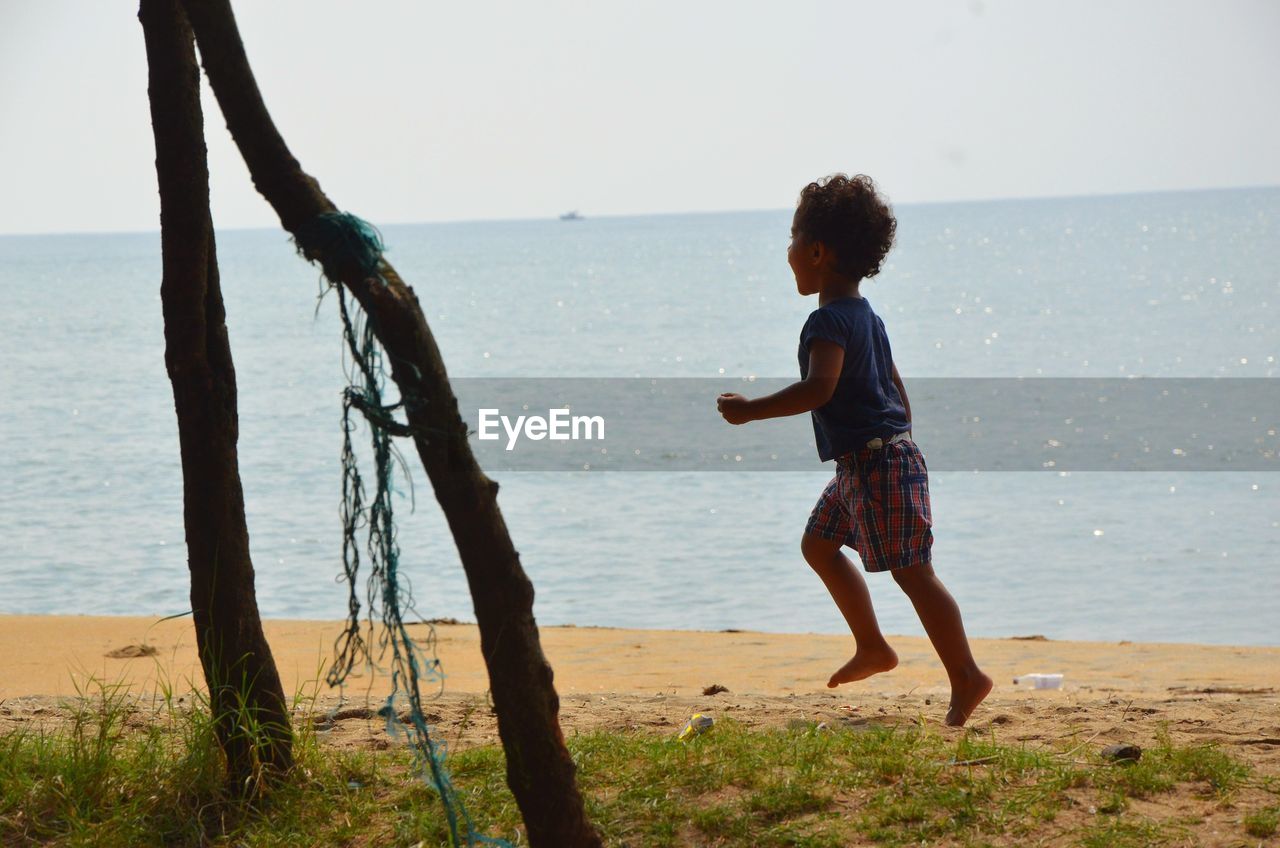 Full length of boy running on shore at beach