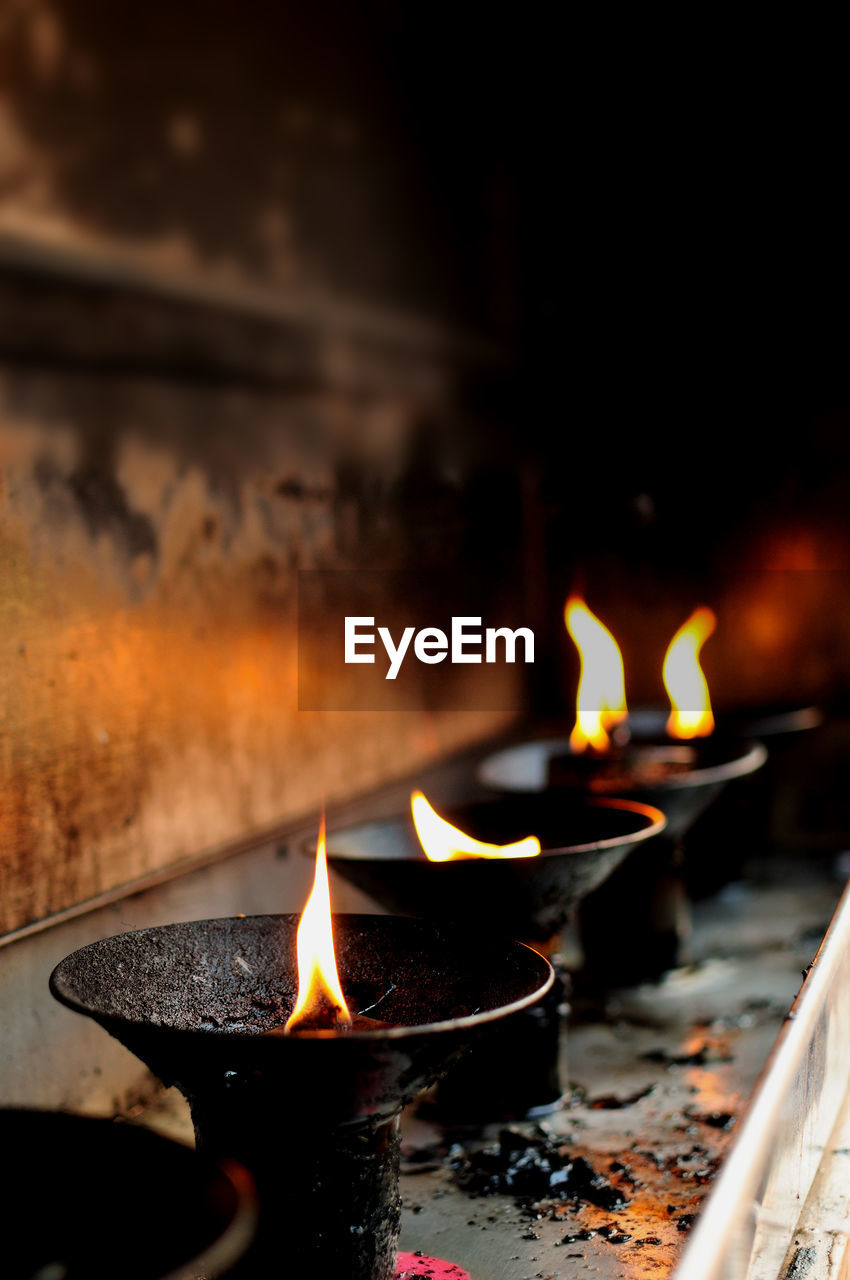 Close-up of lit diyas in temple