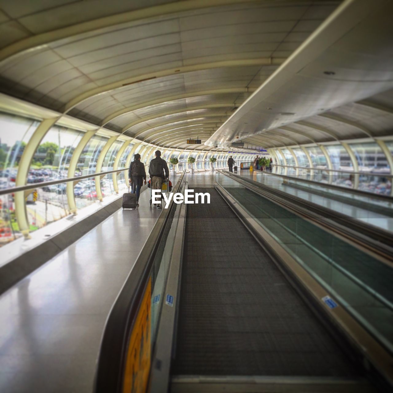 Rear view of people walking on walkway at airport