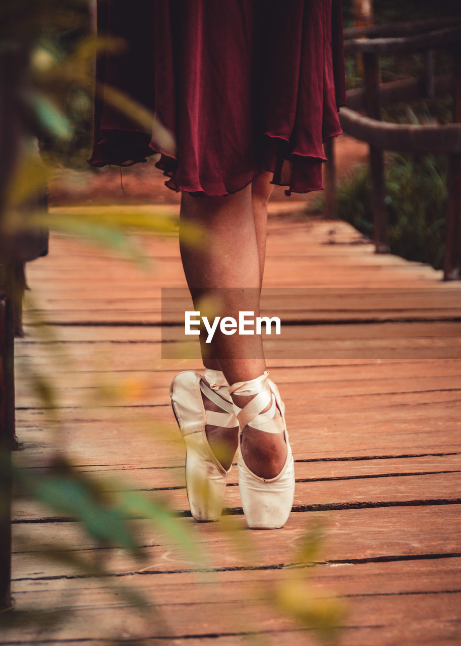 Low section of woman wearing ballet shoe standing on footbridge