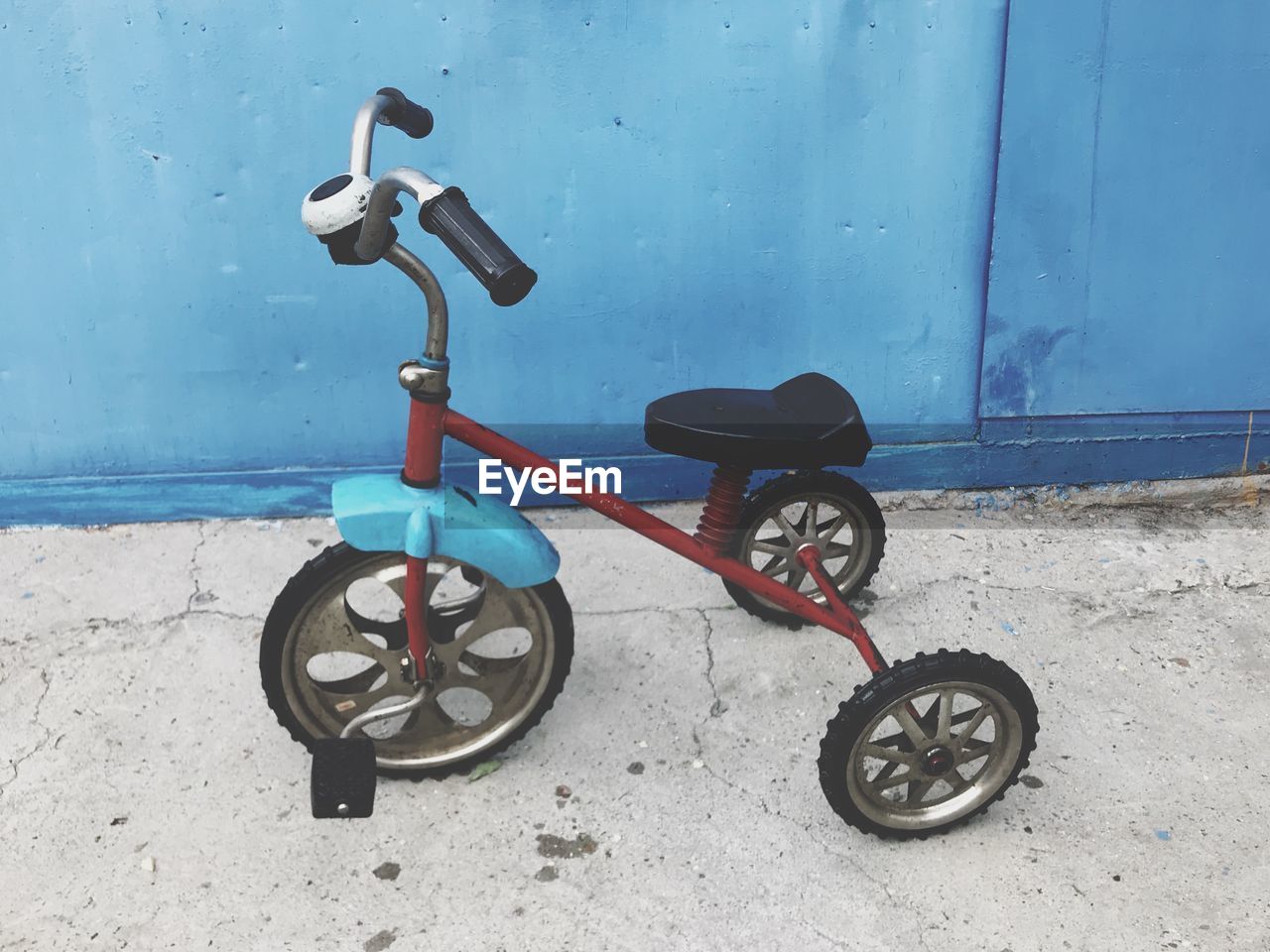 Bicycle parked on footpath against blue wall