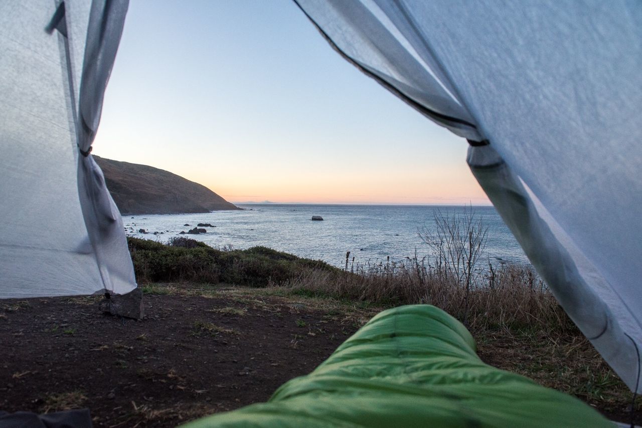 Scenic view of sea against clear sky seen through tent during sunset