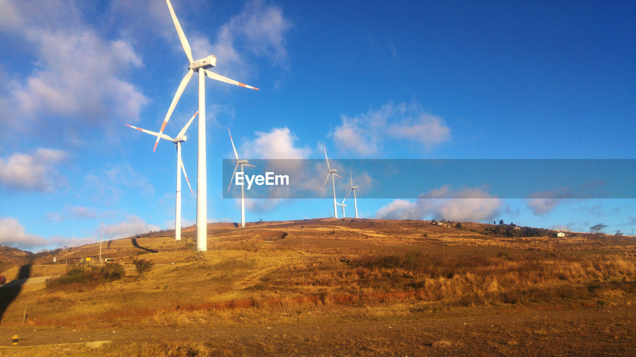 LOW ANGLE VIEW OF WIND TURBINES ON FIELD