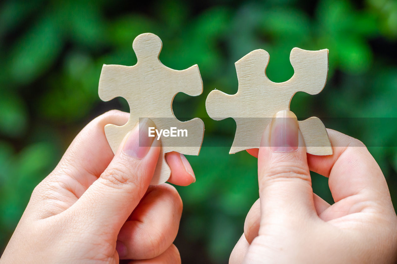 Close-up of hand holding wooden jigsaw pieces