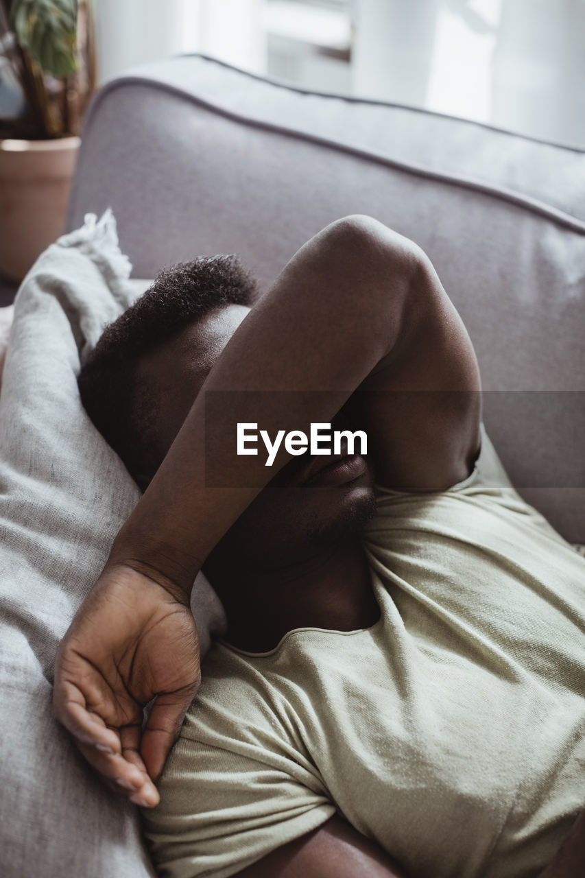 Close-up of man lying on sofa in living room