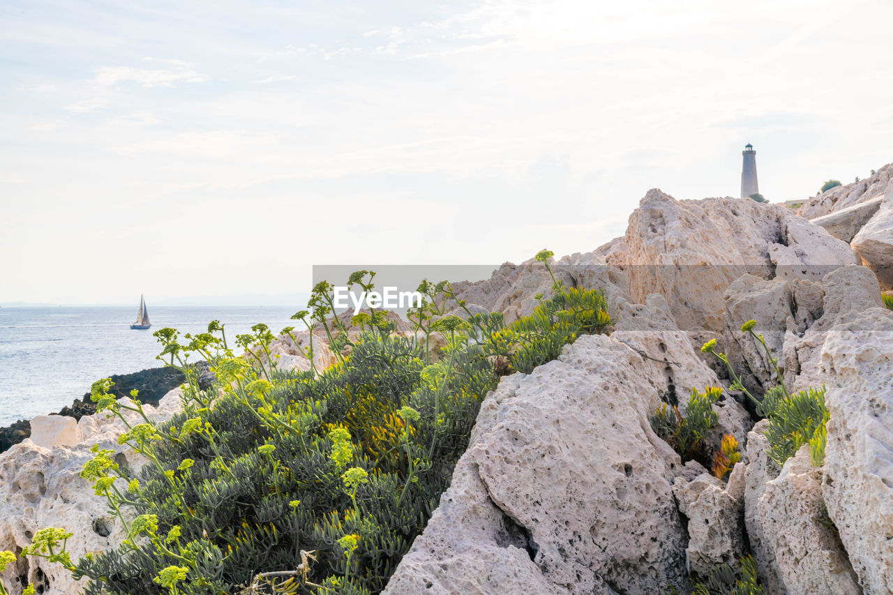 Scenic view of rocks by sea against sky