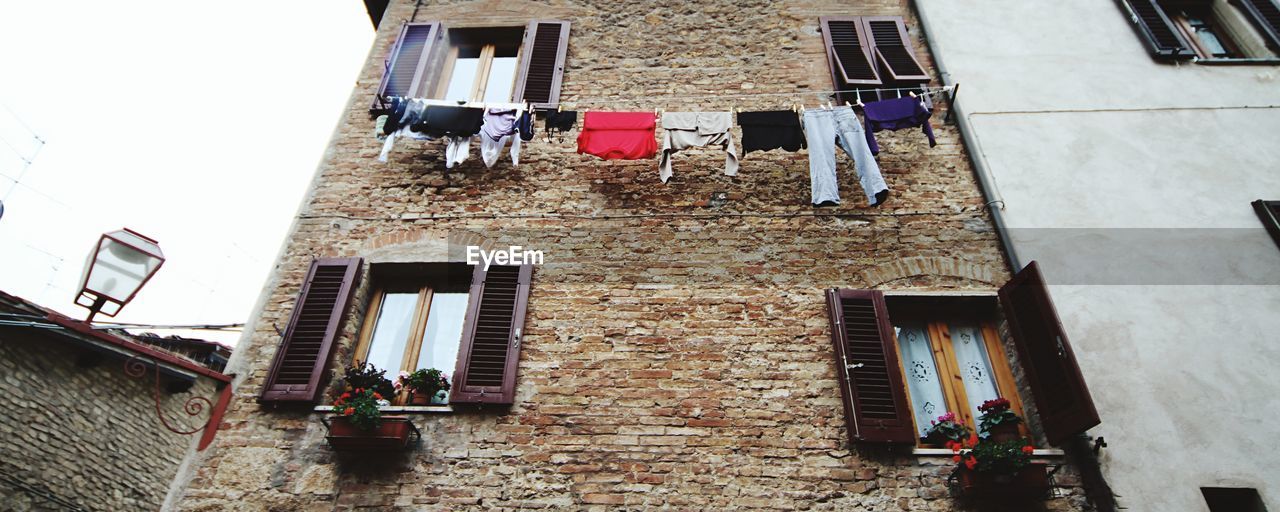 Low angle view of laundry drying on clothesline attached to old city building