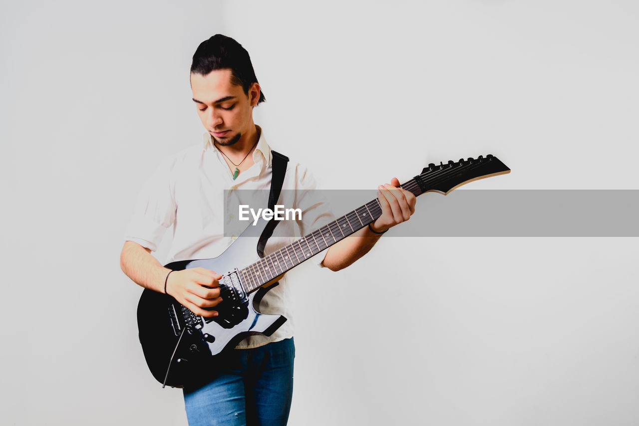 Young man playing guitar against white background