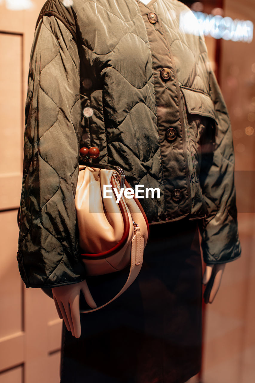 Fancy details of a green jacket with buttons and beige handbag. women's fashion clothing
