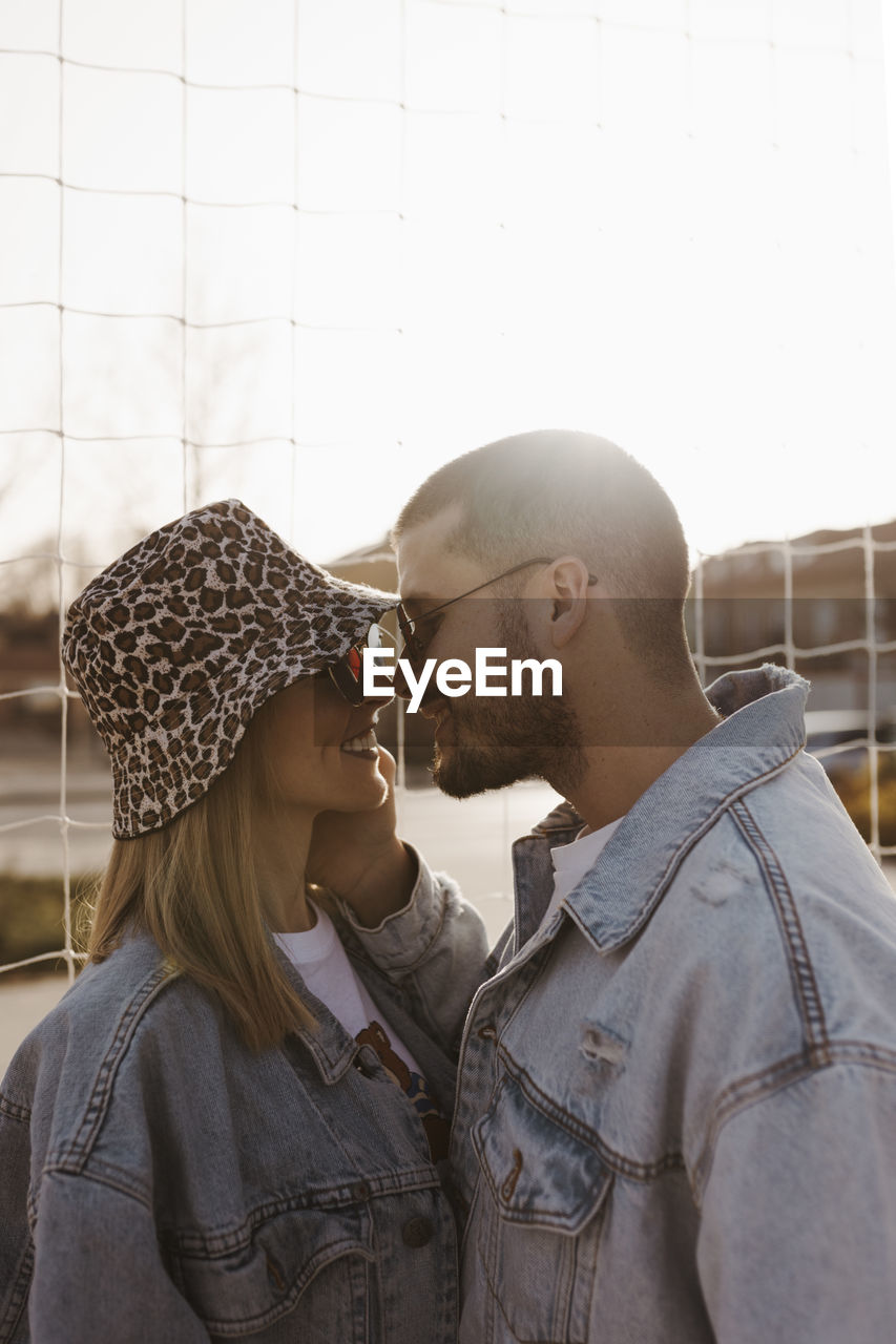 Girlfriend and boyfriend in the fence looking each other and touching noses. happy couple.