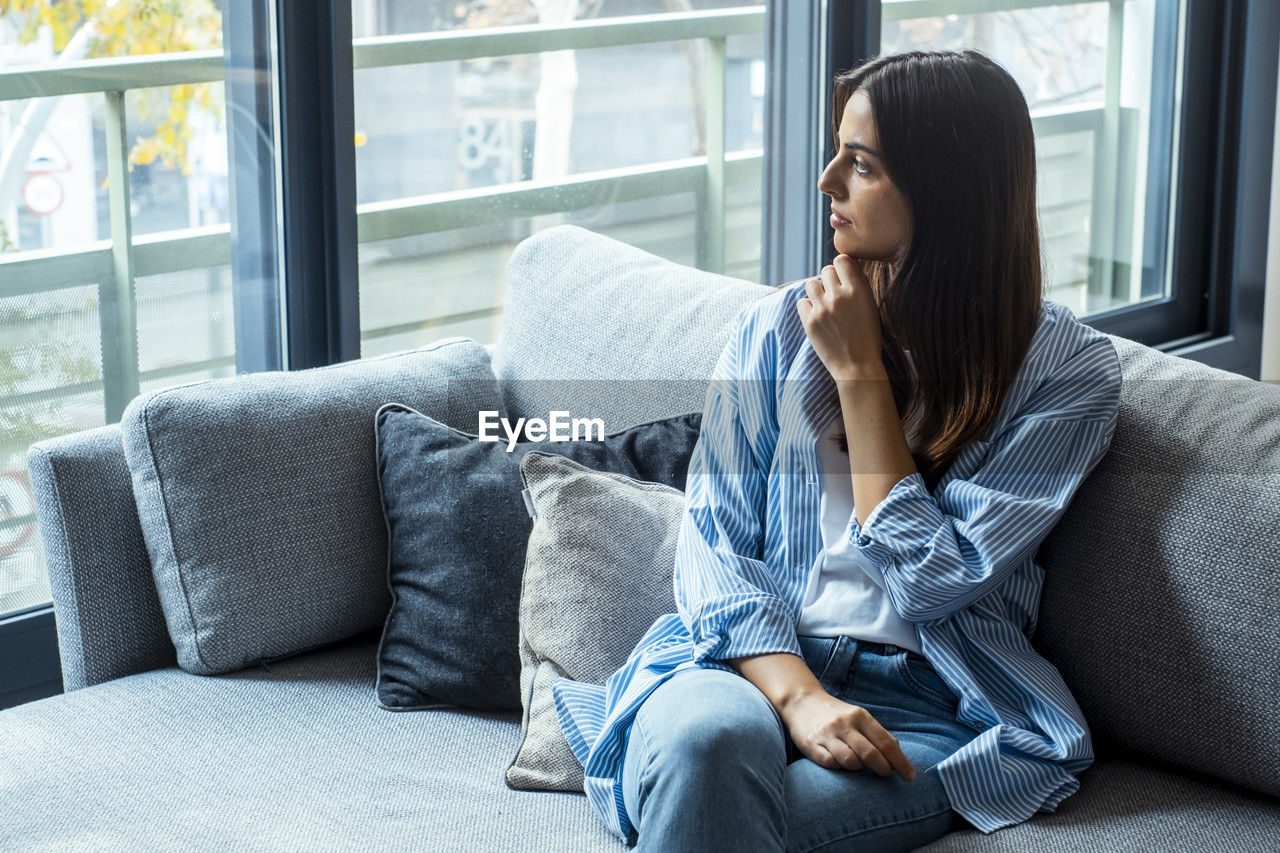 young woman using phone while sitting on sofa