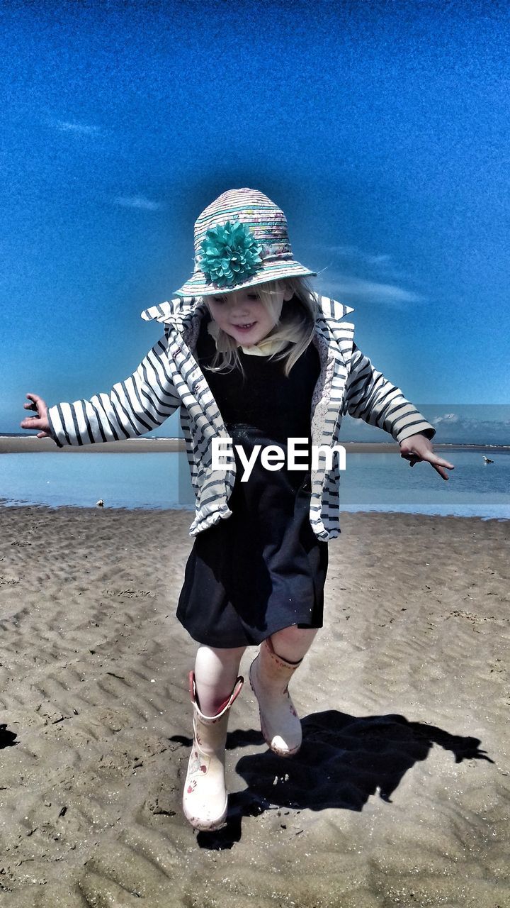 GIRL PLAYING ON SAND AT BEACH