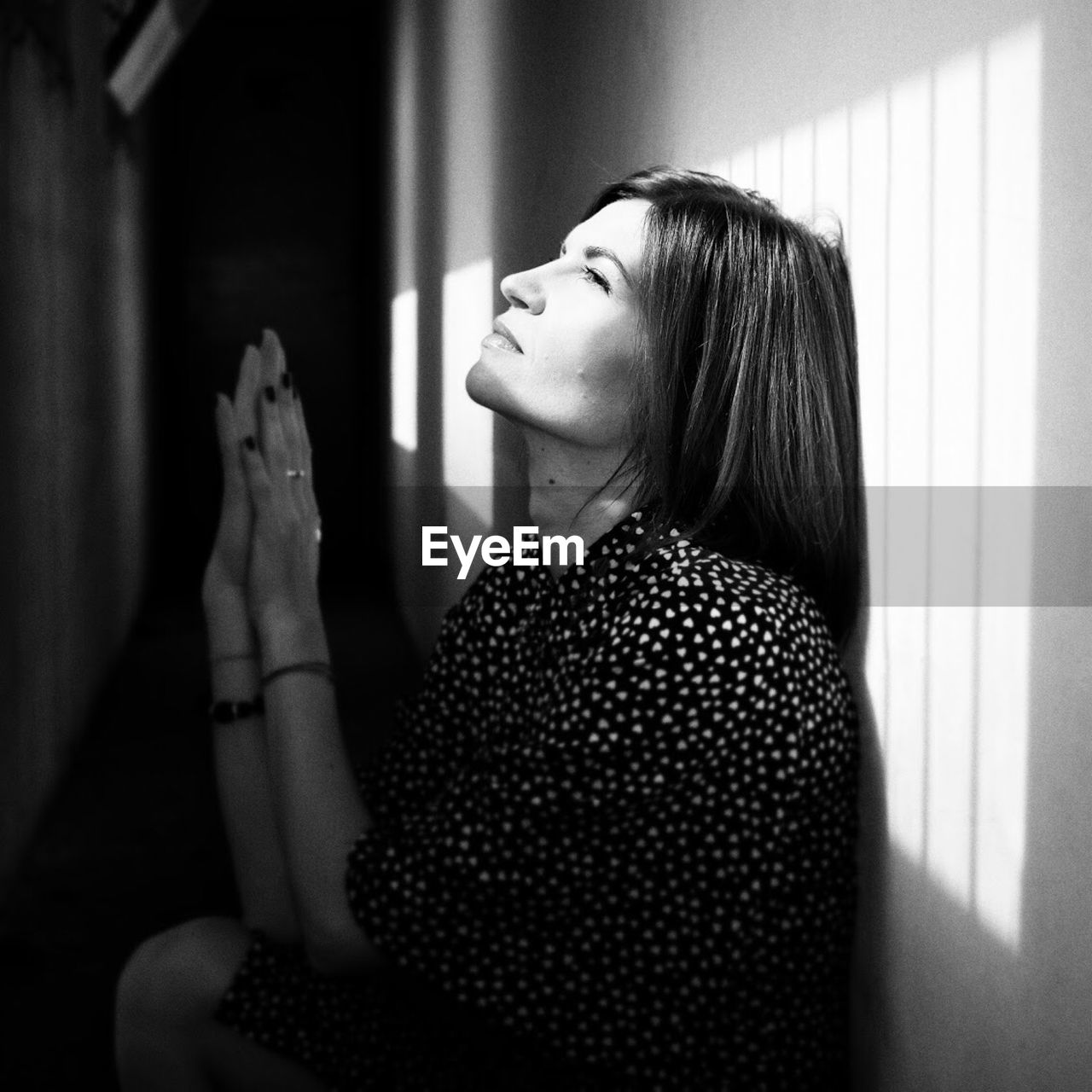 Thoughtful woman sitting against wall