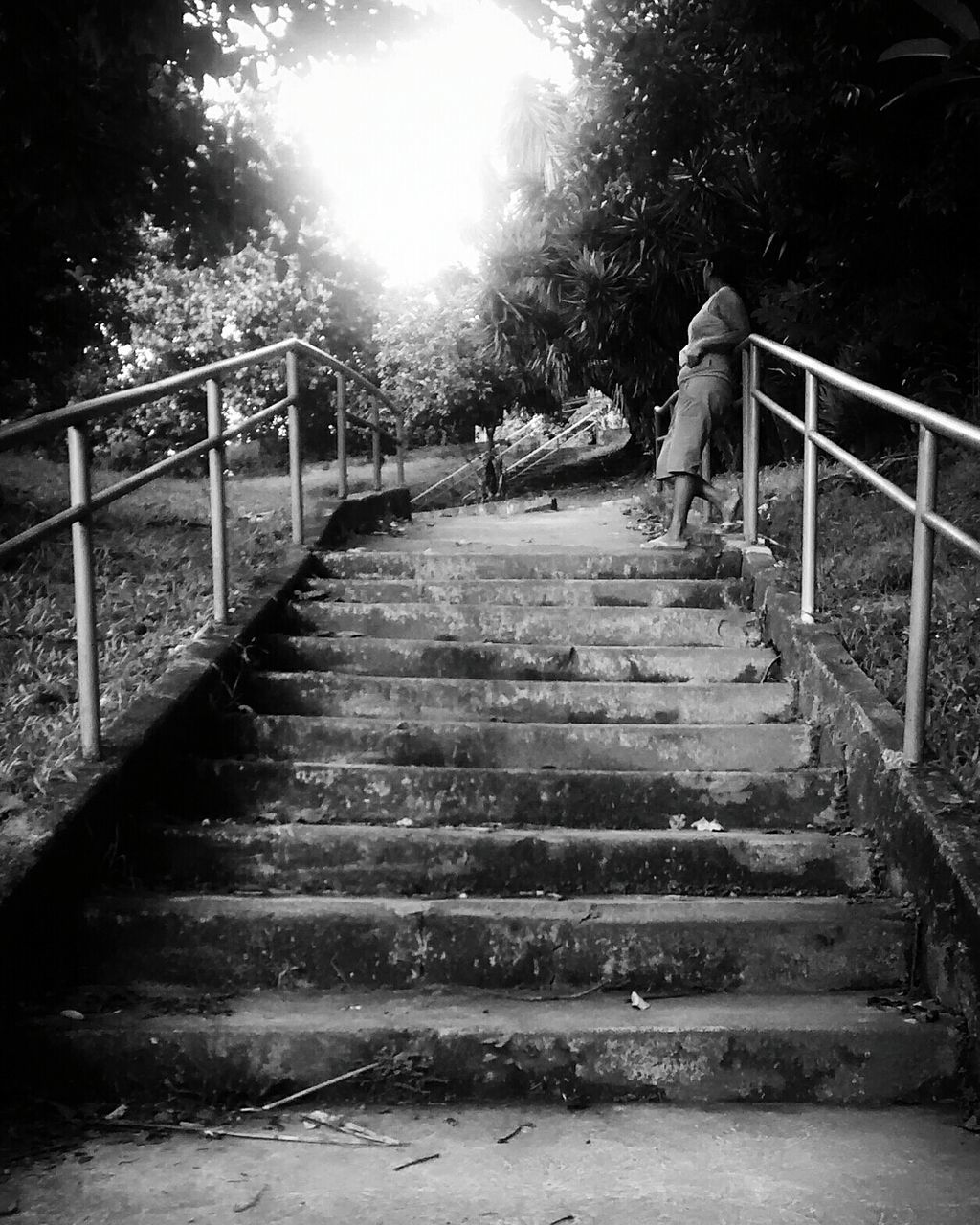 Woman leaning on railing of steps in park