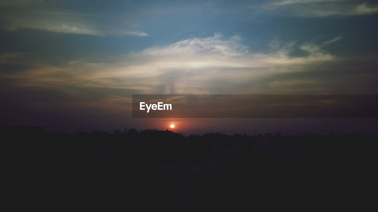 Silhouette cityscape against sky during sunset