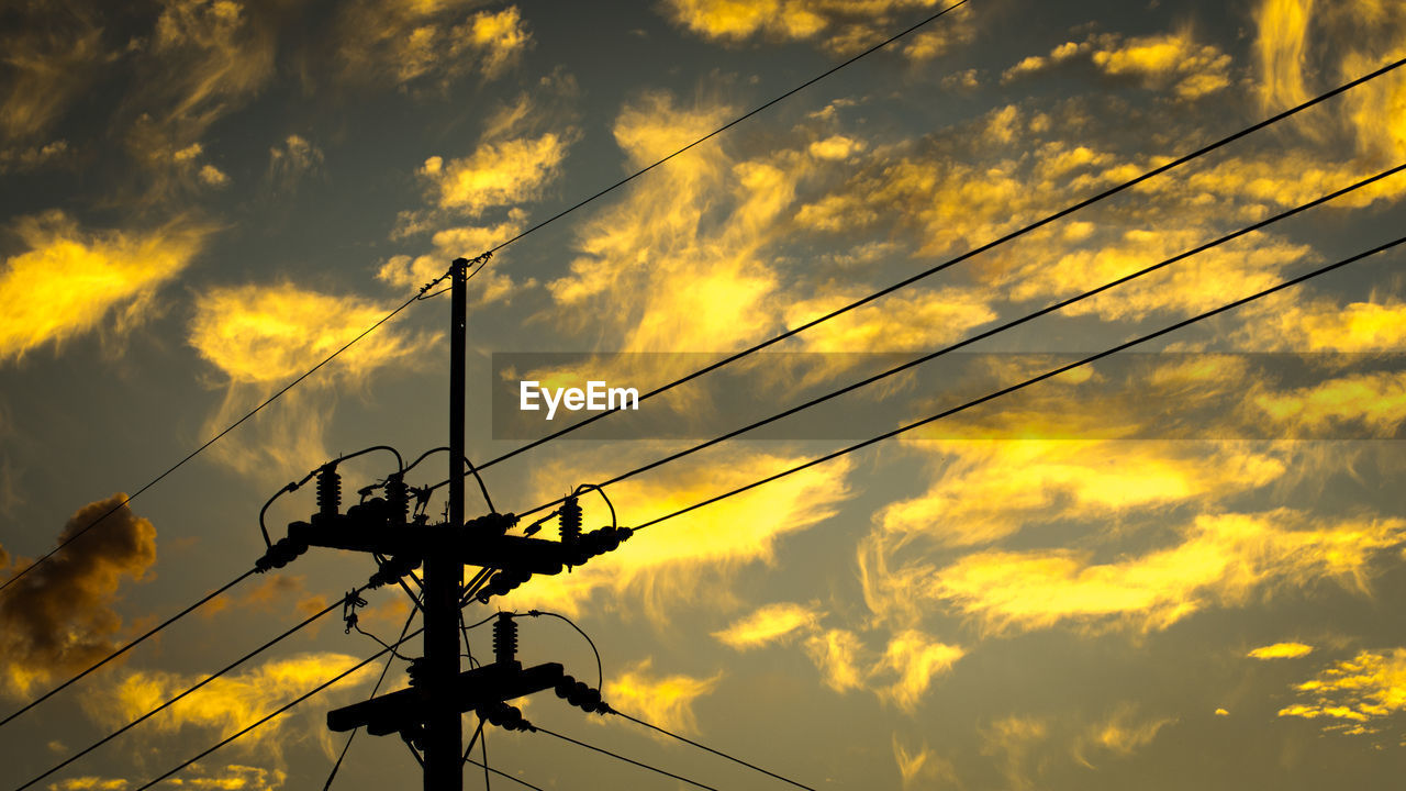 Low angle view of electricity pylon against orange sky