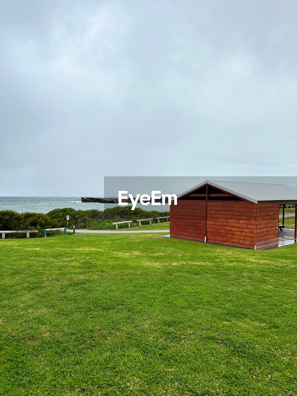 grass, architecture, sky, built structure, building exterior, cloud, rural area, land, green, nature, building, plant, landscape, field, pasture, environment, farm, house, no people, lawn, hill, meadow, grassland, scenics - nature, beauty in nature, rural scene, day, outdoors, agricultural building, prairie, barn, tranquility, water, non-urban scene, residential district, tranquil scene, horizon, hut, plain, agriculture, travel destinations, overcast, copy space