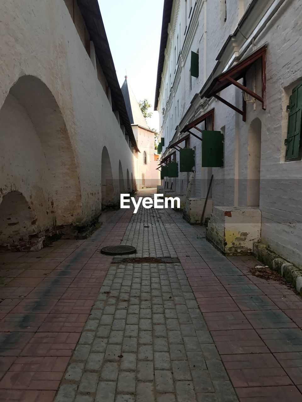 COBBLESTONE STREET AMIDST BUILDINGS IN CITY AGAINST SKY