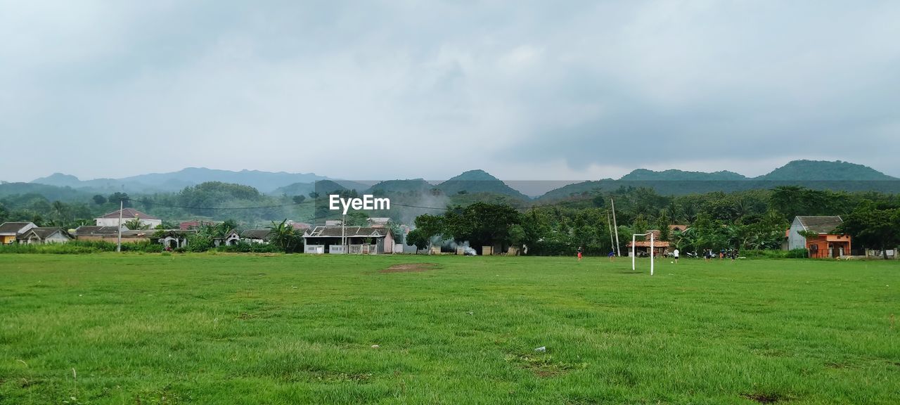 HOUSES ON FIELD AGAINST SKY