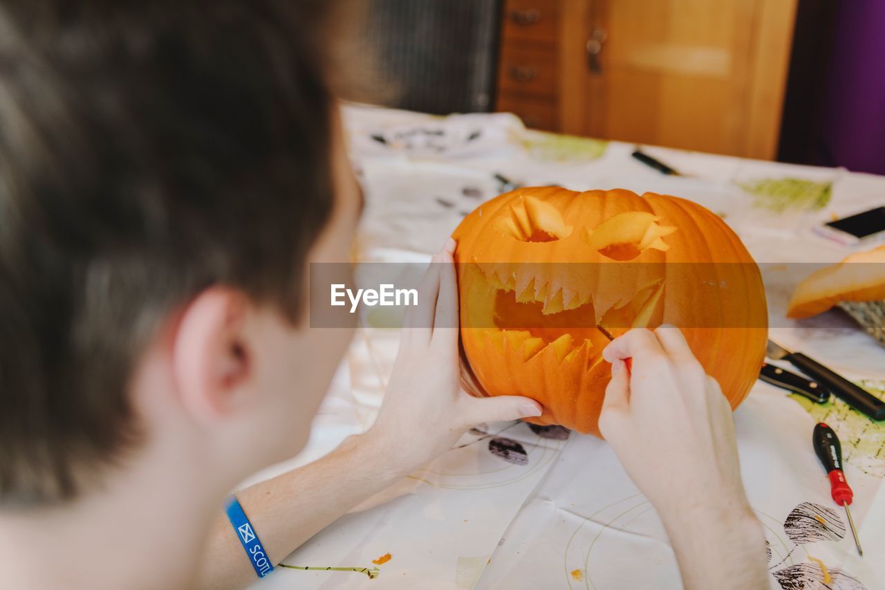 Close-up of baby boy carving pumpkin at table