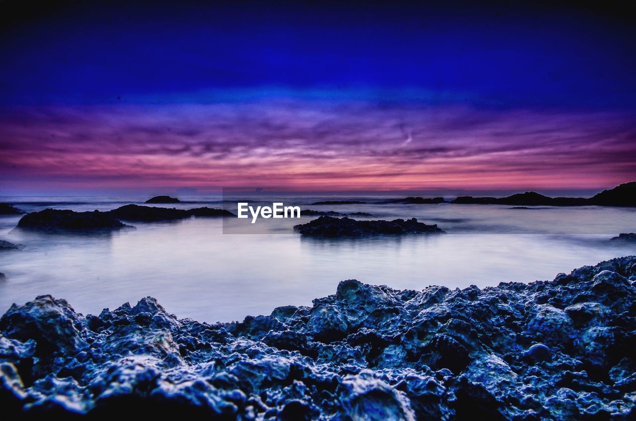 Scenic view of sea against dramatic sky during sunset