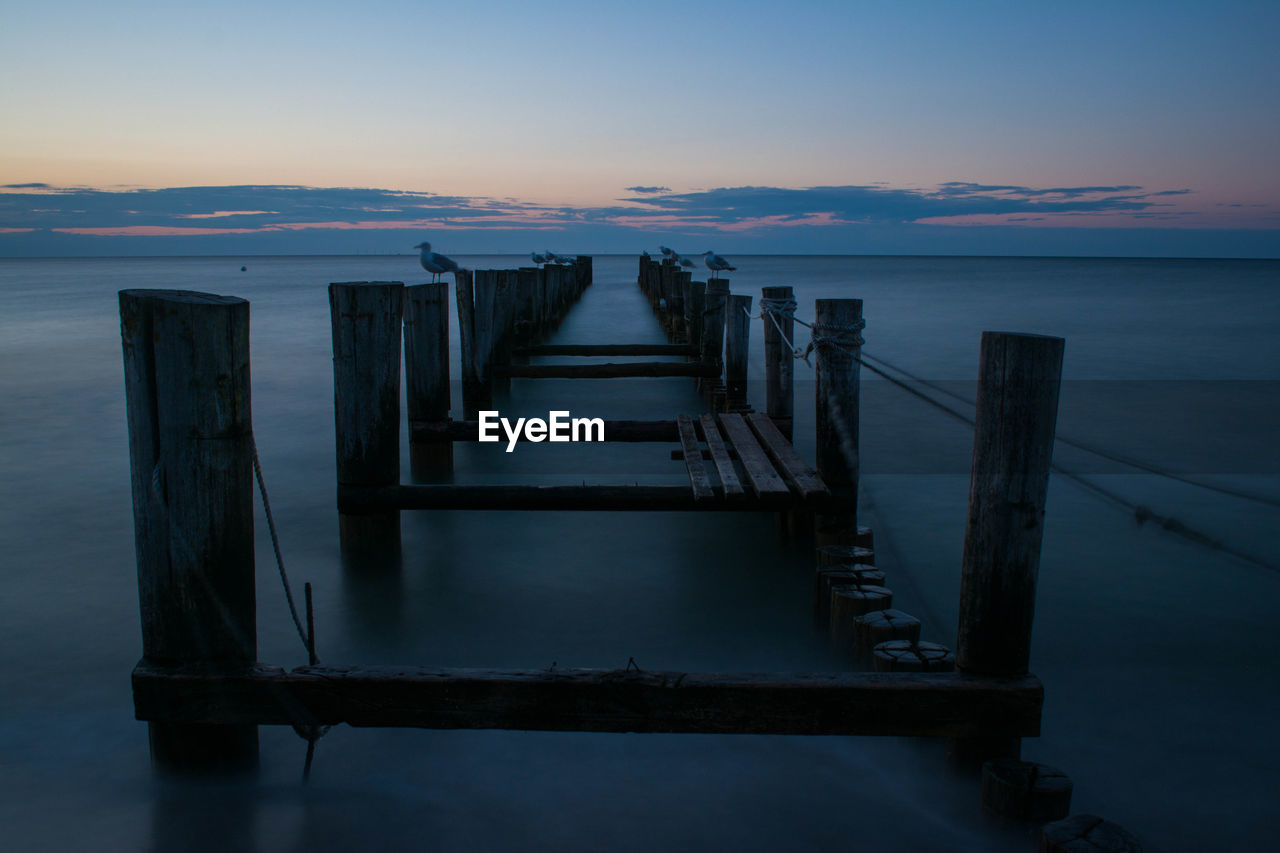 Pier over sea against sky during sunset