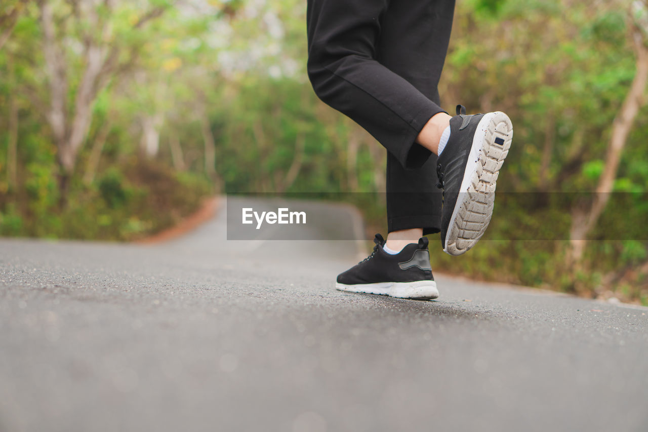 low section of man walking on road