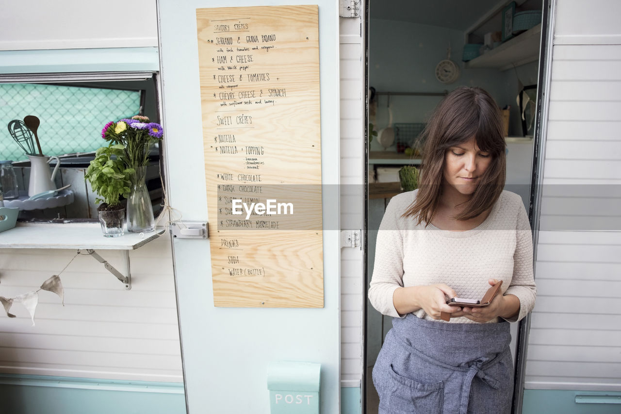 Female owner using smart phone outside food truck