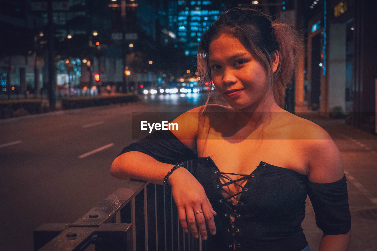 PORTRAIT OF SMILING YOUNG WOMAN ON STREET IN CITY