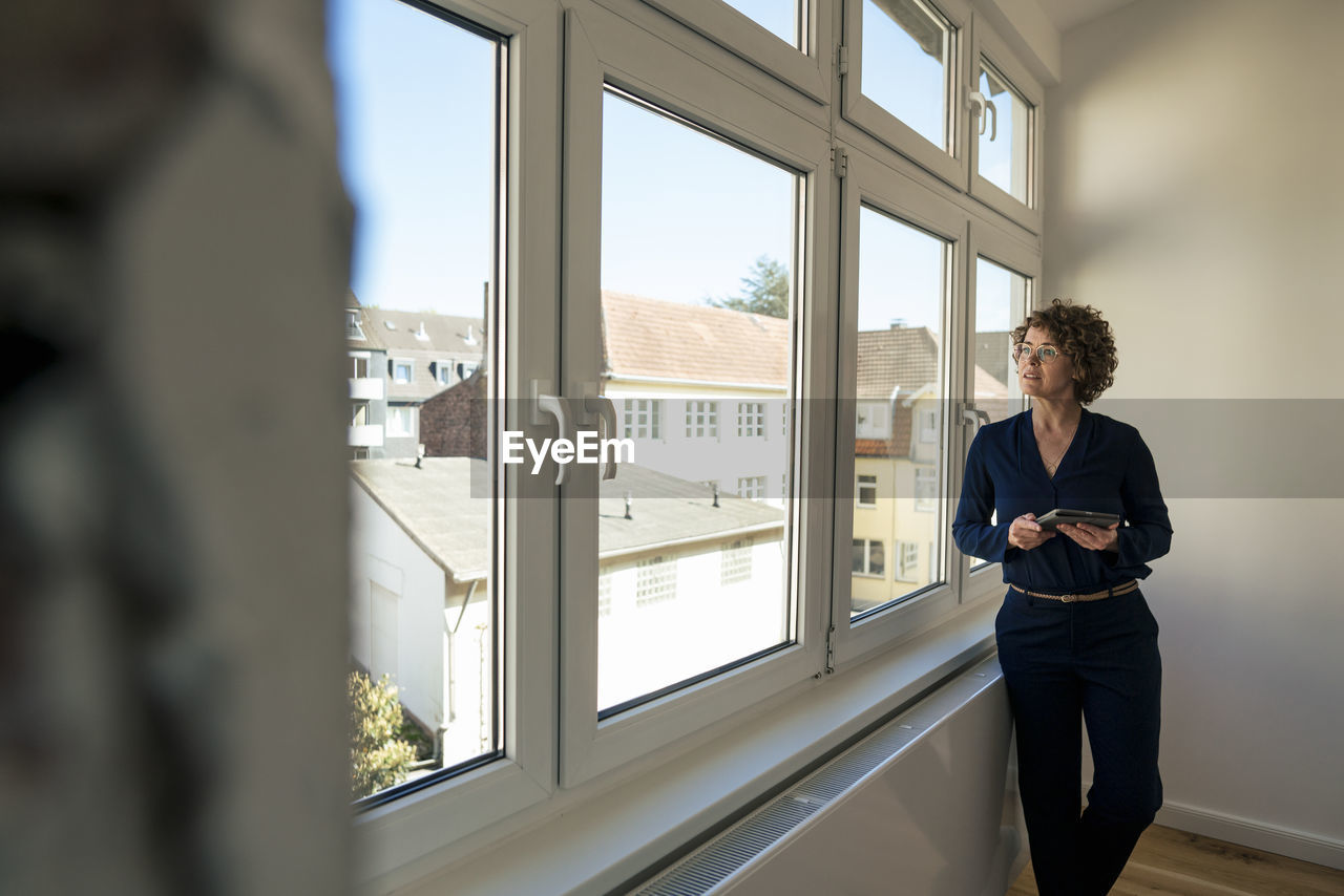 Real estate agent with tablet pc looking through window