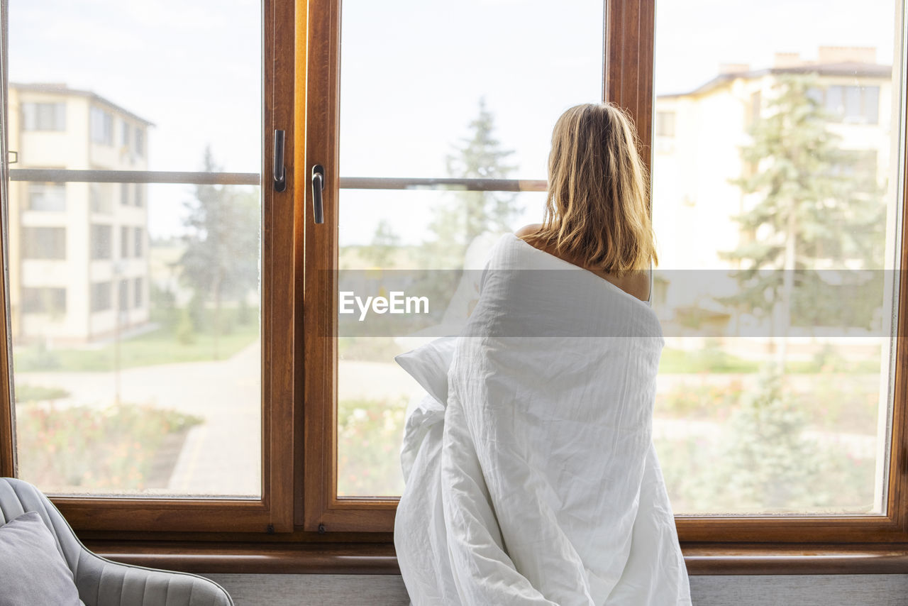 rear view of woman looking through window