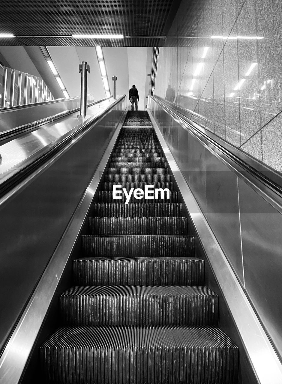 Low angle view of person standing on escalator