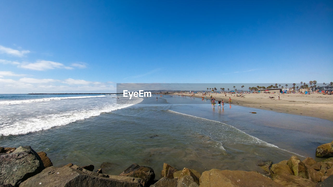 PEOPLE ON BEACH AGAINST BLUE SKY