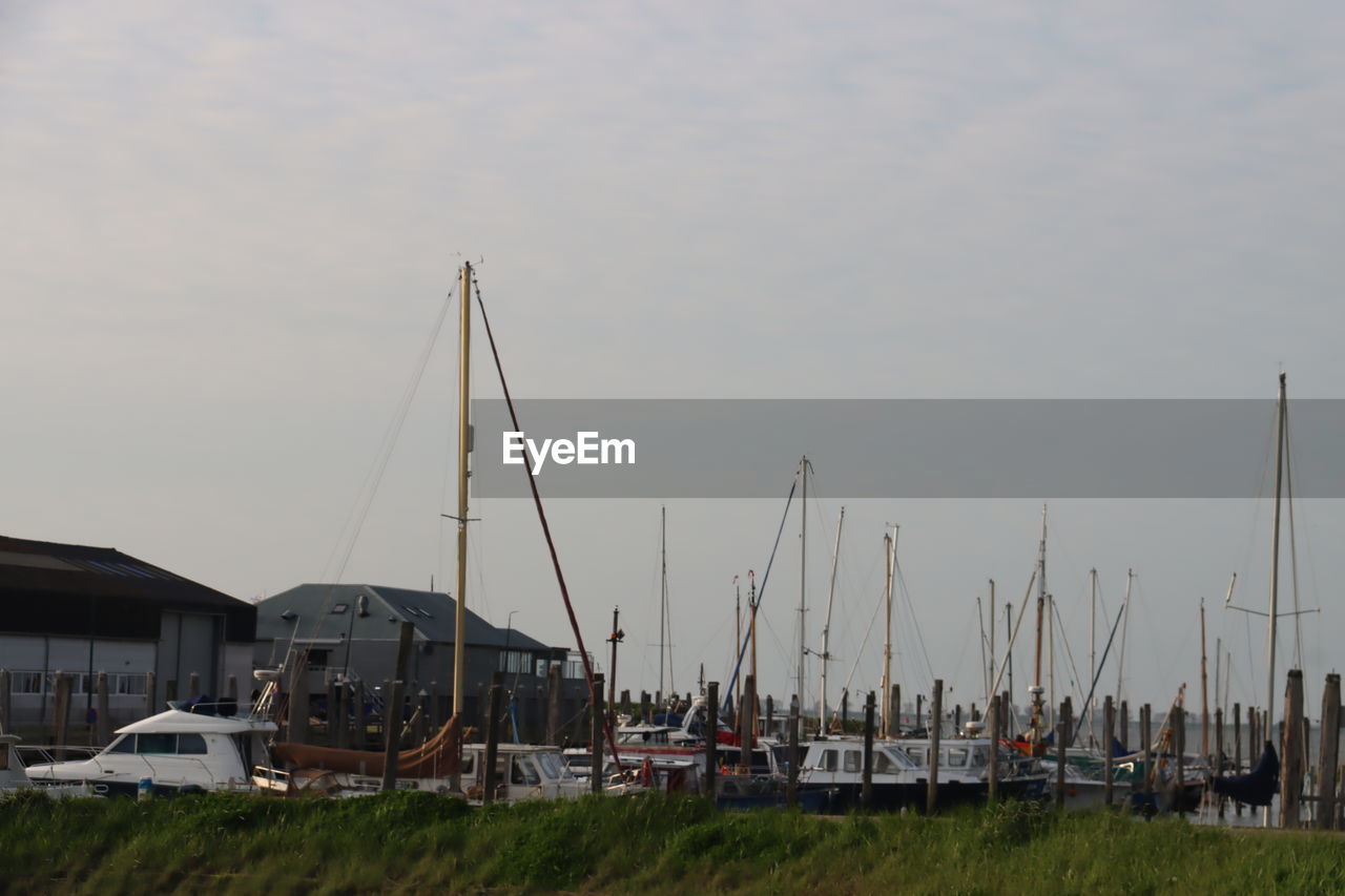 sky, water, nautical vessel, transportation, mode of transportation, architecture, nature, sailboat, mast, dock, no people, built structure, vehicle, boat, marina, pole, sea, harbor, building exterior, ship, moored, day, outdoors, grass, building, watercraft