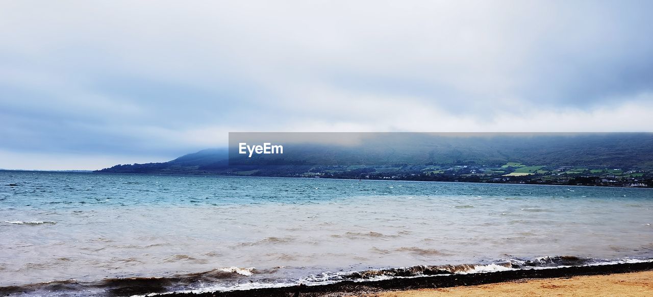 SCENIC VIEW OF SEA BY MOUNTAINS AGAINST SKY