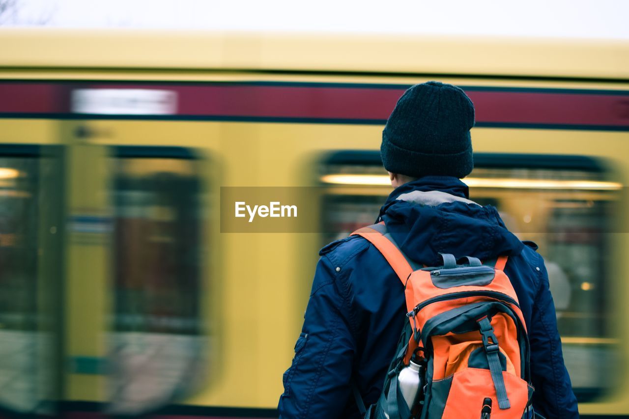 Rear view of man standing by train at railroad station