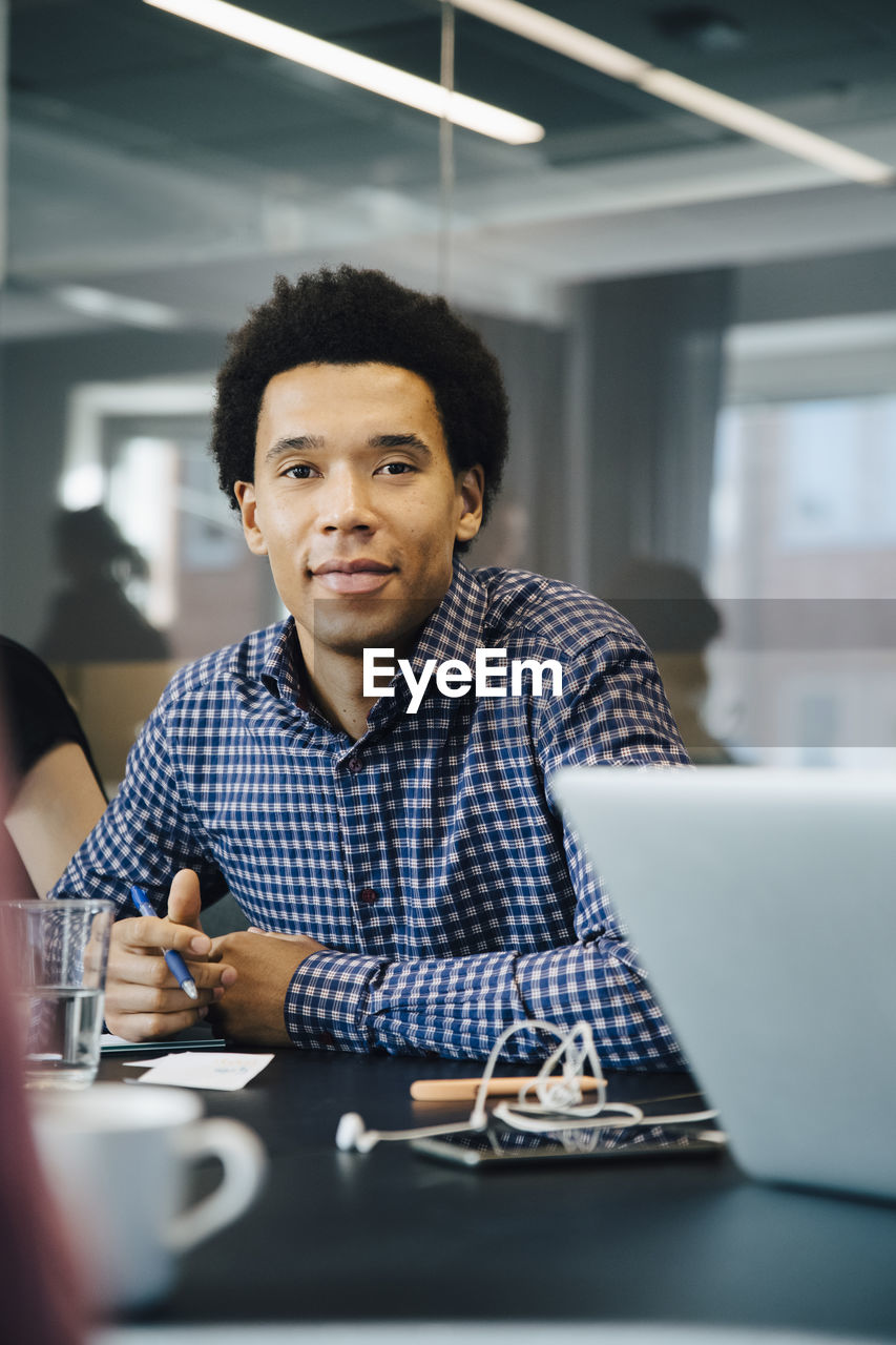 Portrait of confident businessman sitting at conference table in board room