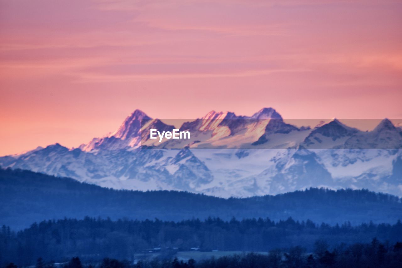 mountain, scenics - nature, beauty in nature, landscape, environment, mountain range, winter, snow, sunrise, sky, cold temperature, dawn, nature, mountain peak, morning, tranquility, snowcapped mountain, land, tranquil scene, tree, cloud, travel destinations, fog, forest, twilight, plant, no people, travel, sun, idyllic, wilderness, outdoors, non-urban scene, coniferous tree, pine tree, dramatic sky, ridge, plateau, tourism, summit, pine woodland, pinaceae, rural scene, sunlight, panoramic, valley