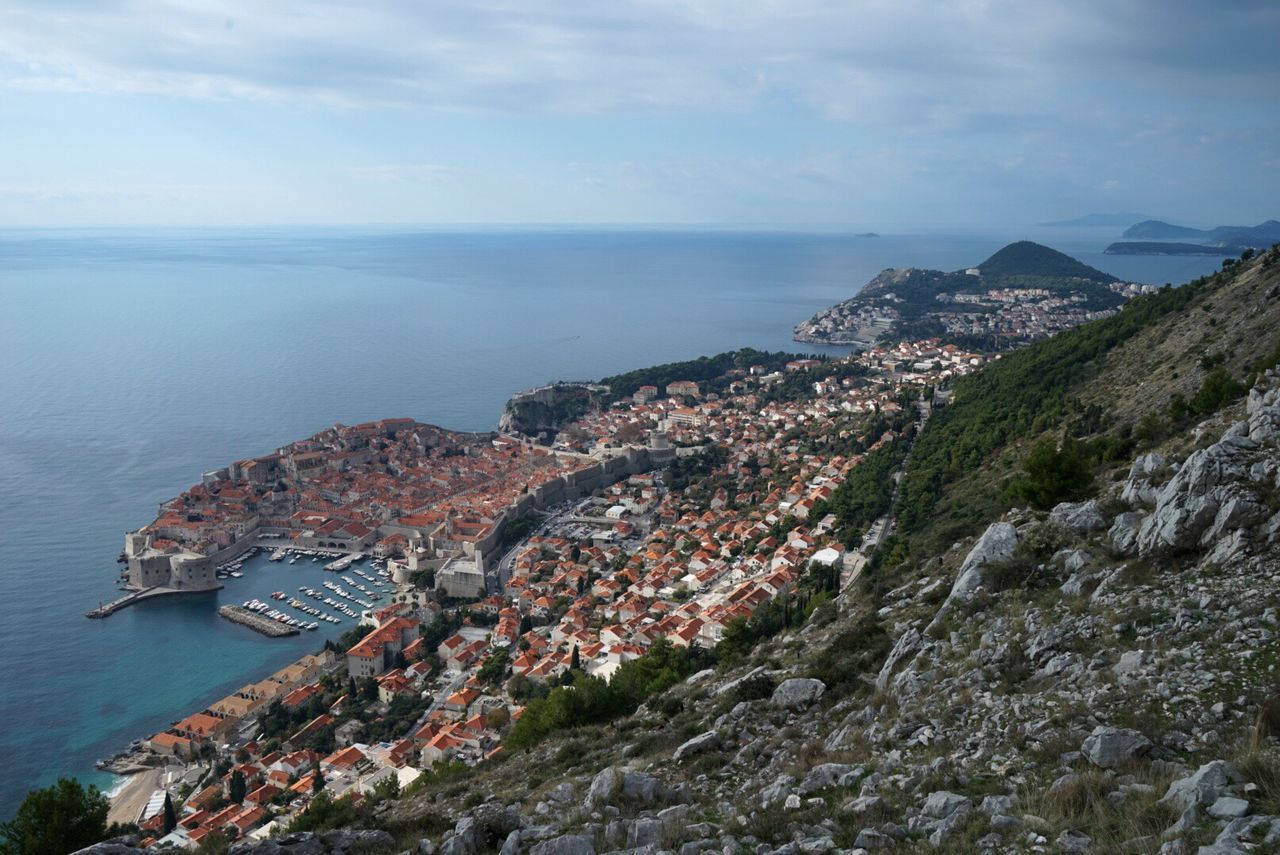 High angle view of sea by mountain against sky