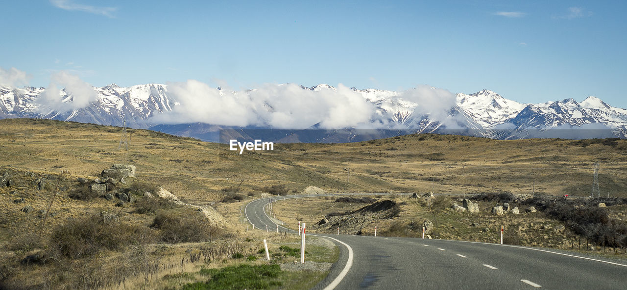 Road leading towards snowcapped mountains against sky