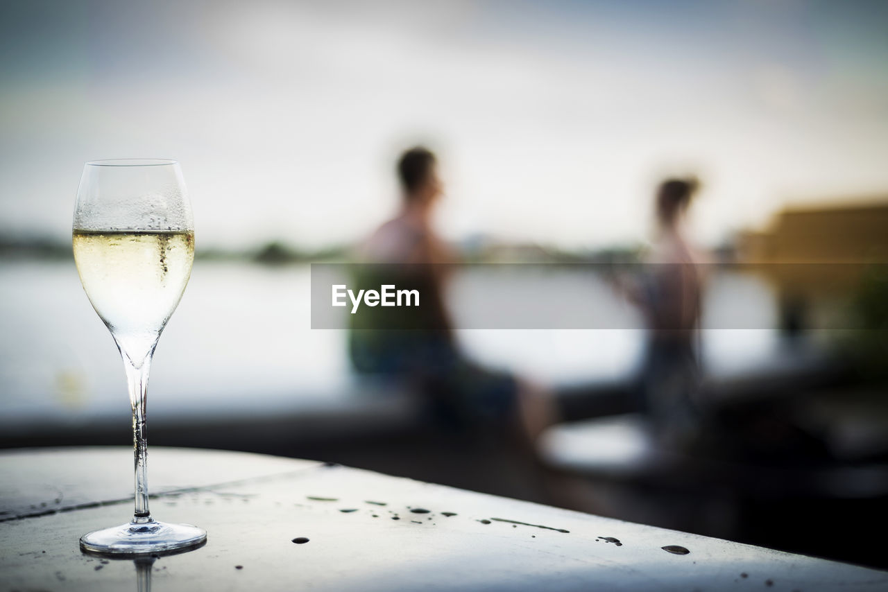 food and drink, refreshment, focus on foreground, drink, adult, alcohol, glass, women, wine glass, sky, table, two people, water, nature, wine, day, togetherness, outdoors, relaxation, men, household equipment, young adult, drinking glass, leisure activity, enjoyment, female, food, emotion