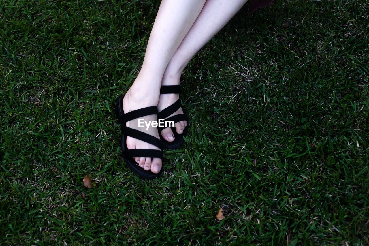 Low section of woman relaxing on grassy field