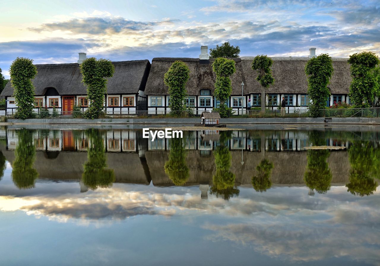 REFLECTION OF HOUSE AND TREES IN LAKE