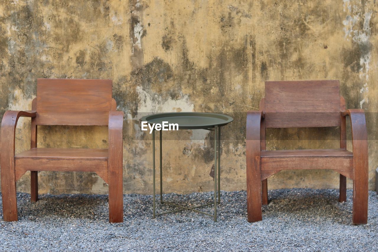 EMPTY CHAIR AND TABLE AGAINST WALL